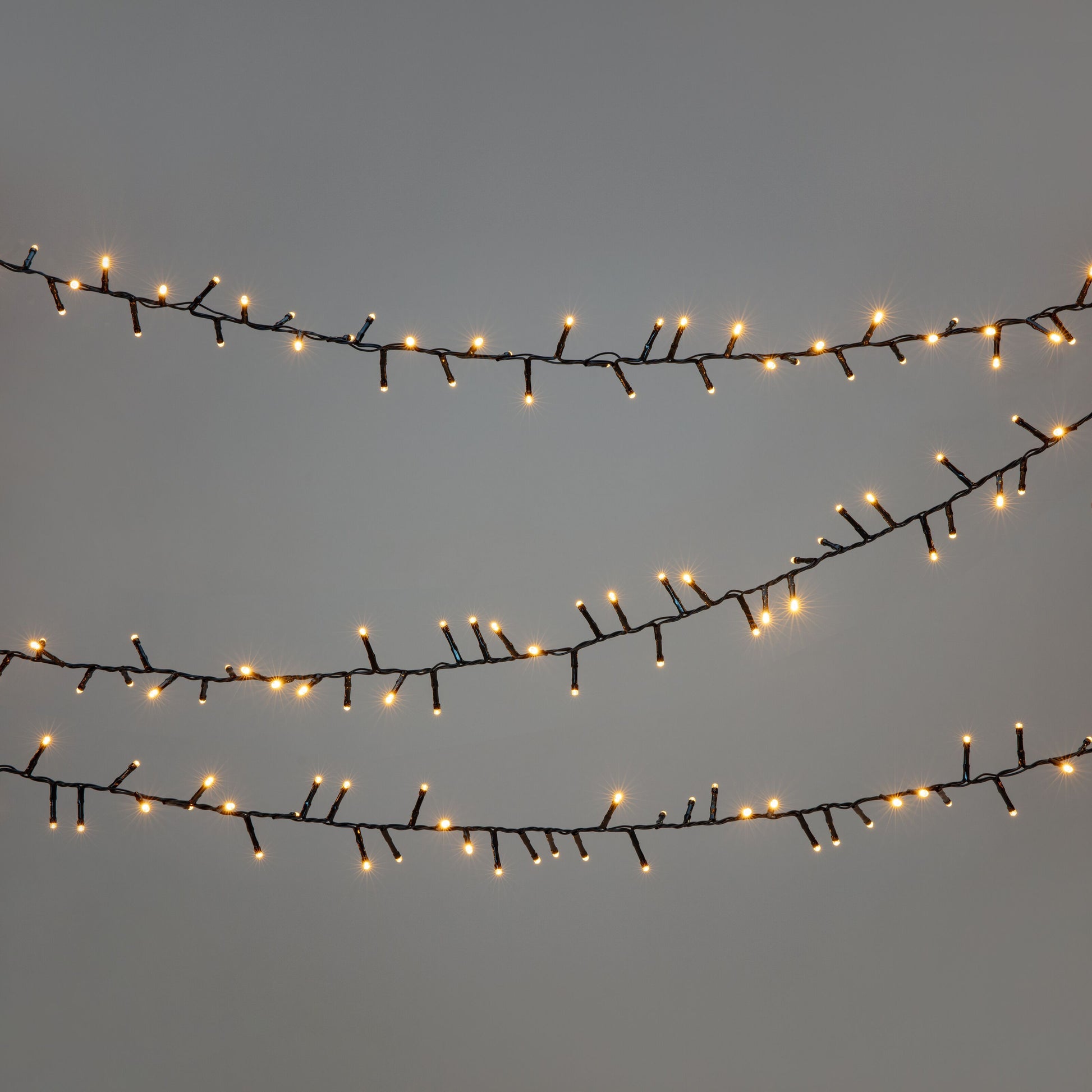 Lyskæde 2000 LED 40 m sort hænger vandret, lyser med varm hvid farve, synlige sorte ledninger.
