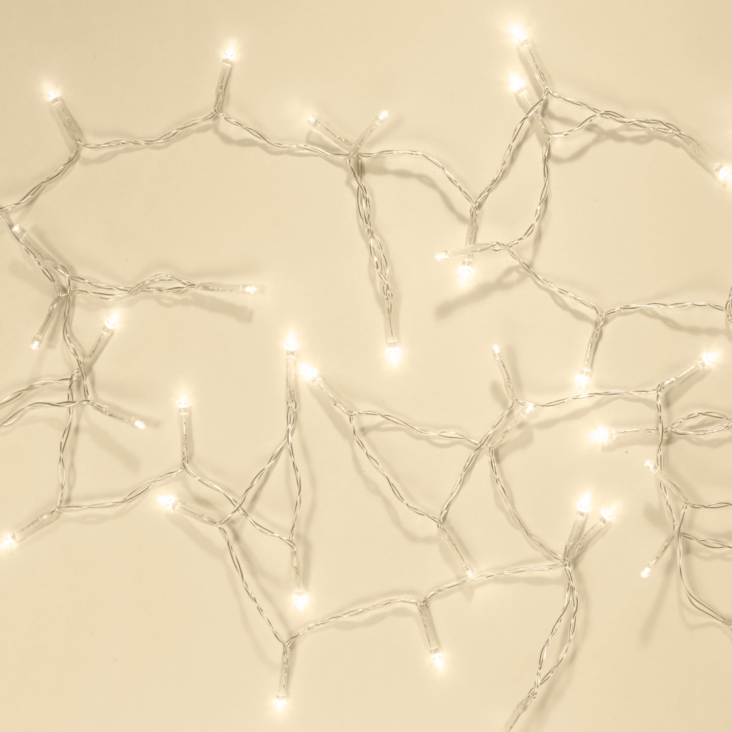 Lyskæde 48 LED 3,5m klar med snoede ledninger og klare pærer, udstrakt på beige flade.