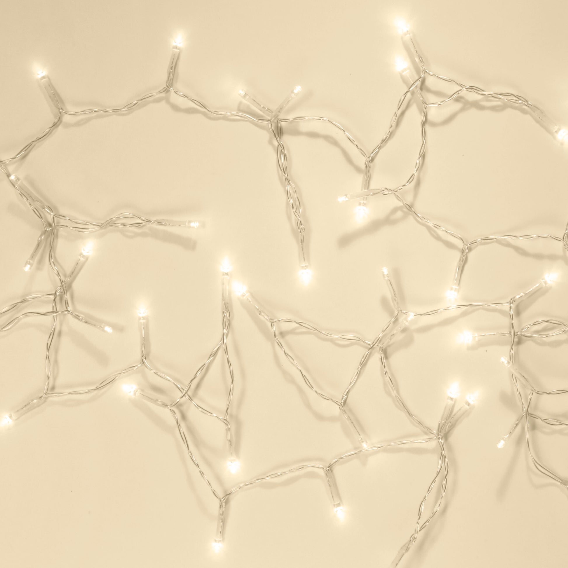 Lyskæde 48 LED 3,5m klar med snoede ledninger og klare pærer, udstrakt på beige flade.