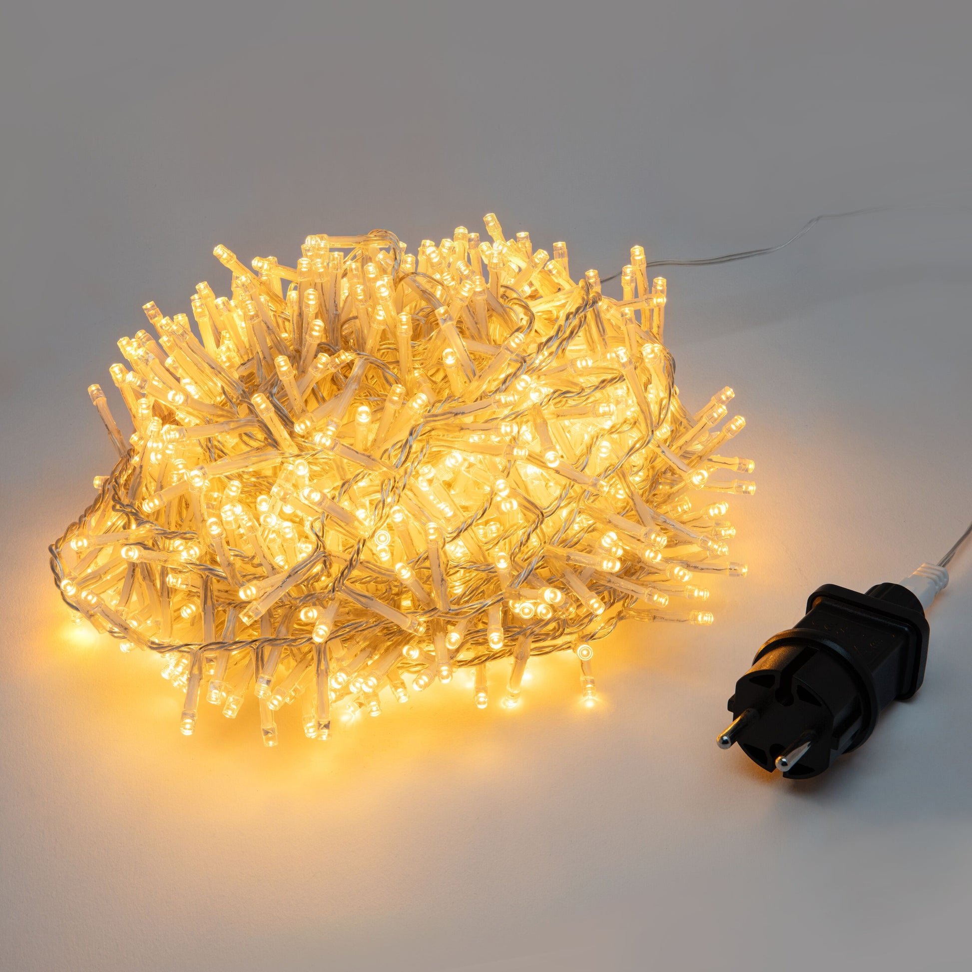 Lyskæde 1000 LED 20m klar med sort strømstik synlig, LED'erne lyser på flad overflade.