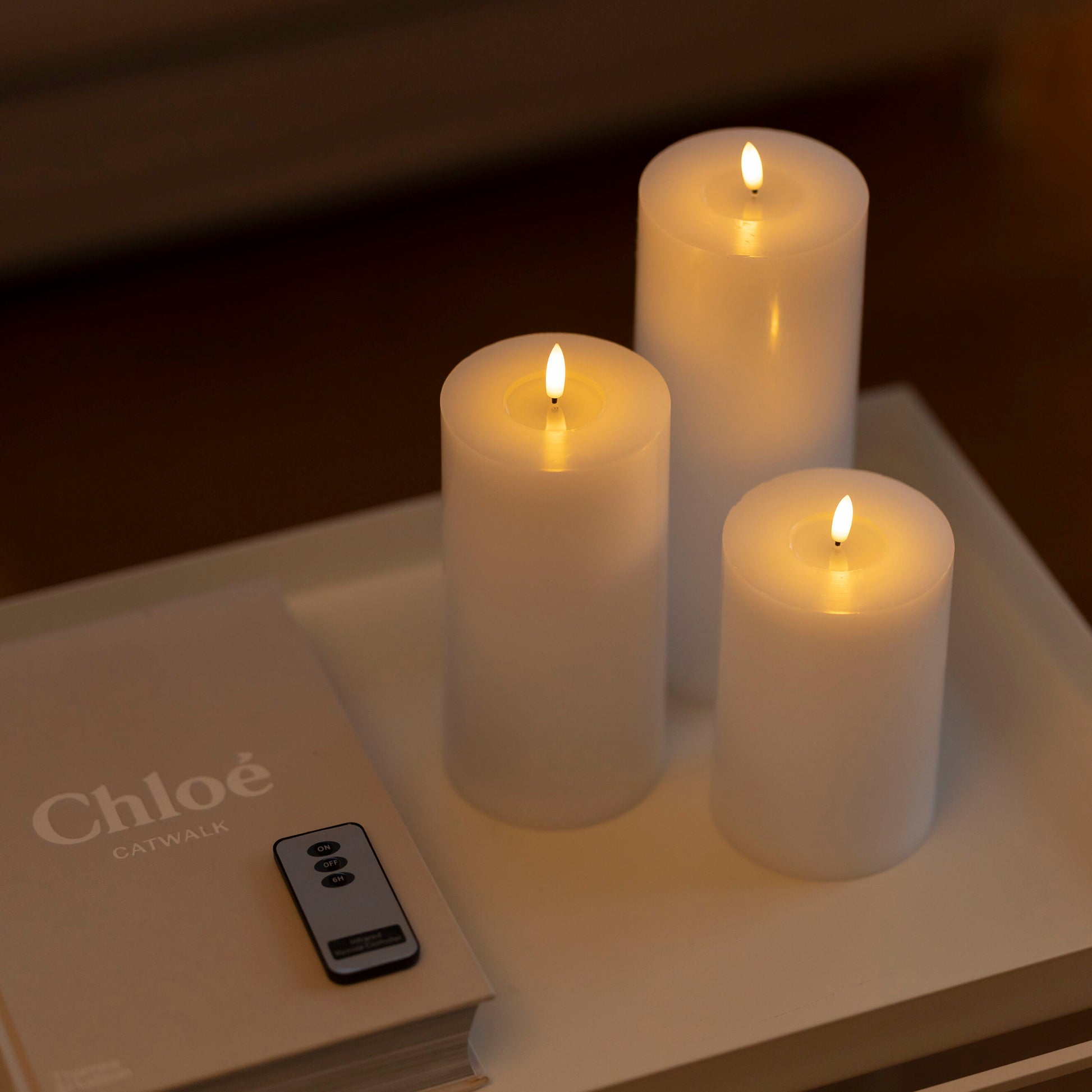 LED Bloklys 3-pak på bakke ved siden af bogen "Chloé Catwalk" og fjernbetjening.