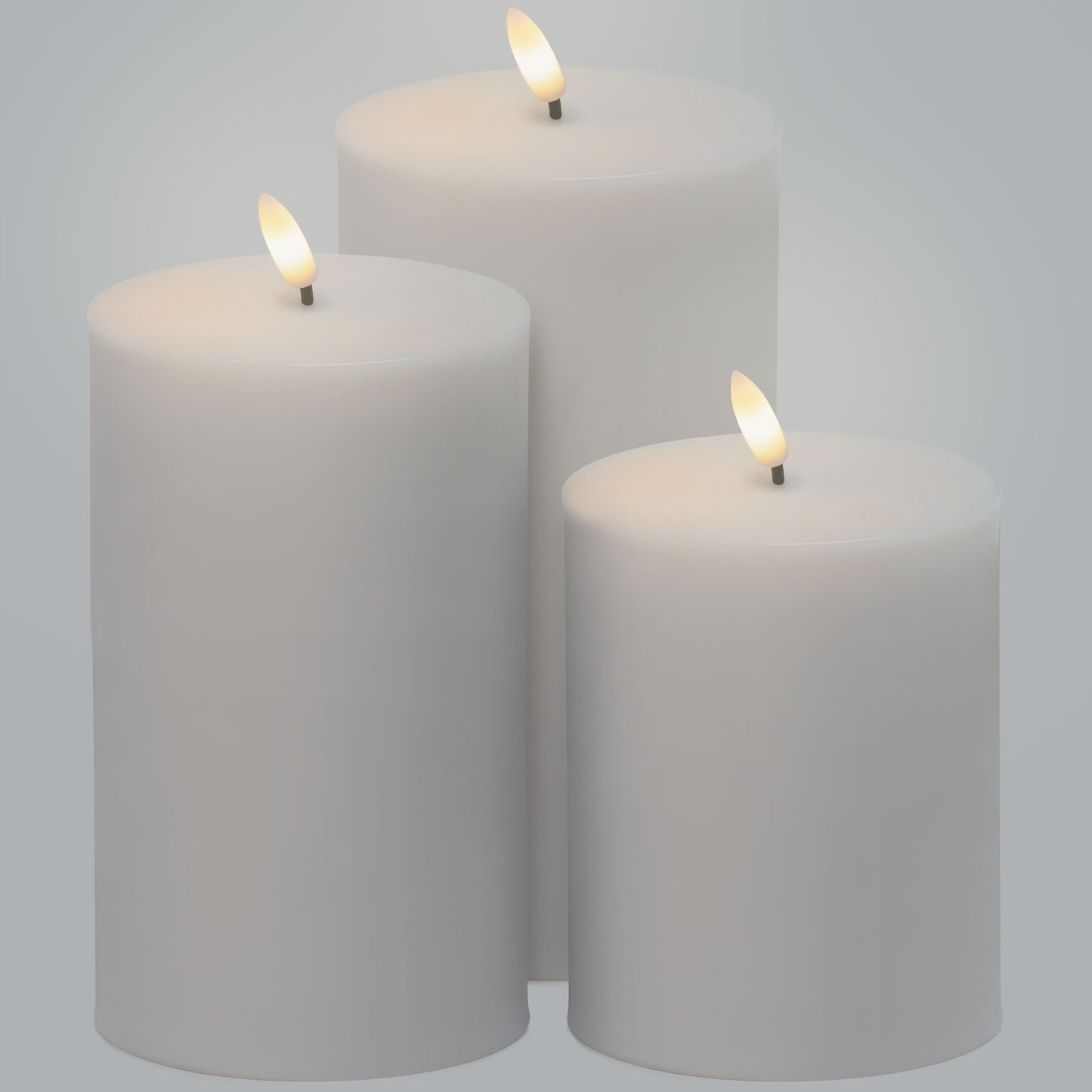 LED Bloklys 3-pak, tre bloklys i forskellige højder med varm flamme, samlet på ensfarvet lys baggrund.