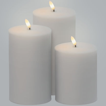 LED Bloklys 3-pak, tre bloklys i forskellige højder med varm flamme, samlet på ensfarvet lys baggrund.