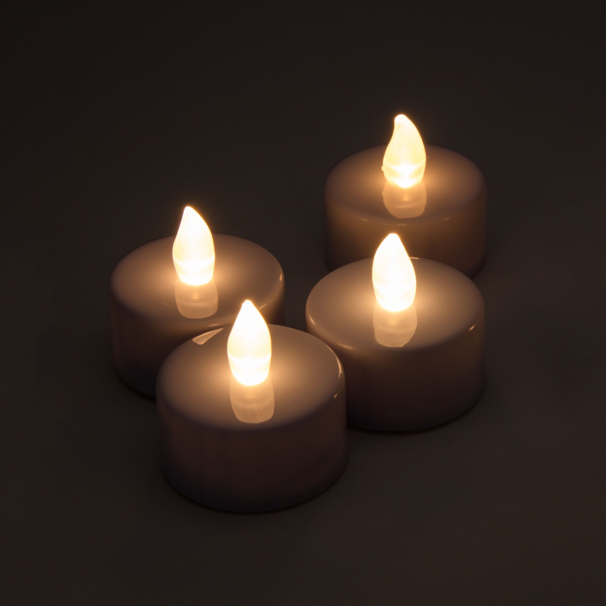LED Varmelys 4-pak med flammeformede glødepærer, varmt lys, placeret på mørk overflade.