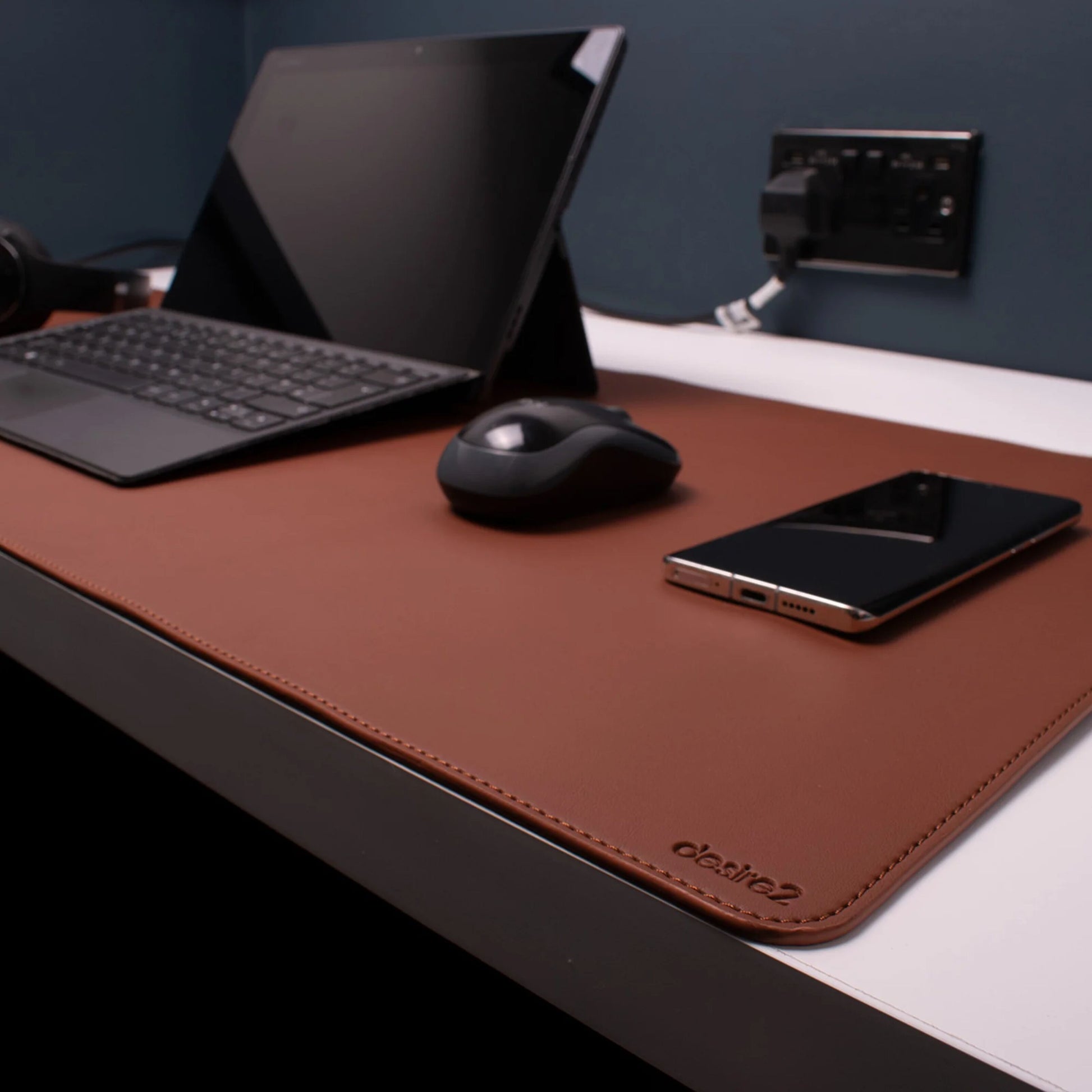 Desire2 skrivebordsmåtte vegansk læder 900x400 mm brun på hvidt bord med laptop tastatur trådløs mus smartphone.