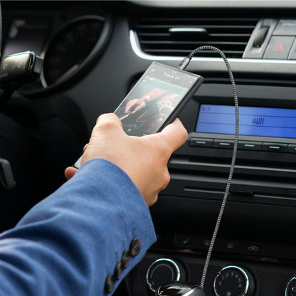 Goobay AUX lydkabel 3,5 mm 2 m tilsluttet smartphone og bilstereo, musikafspiller synlig på mobilskærm.