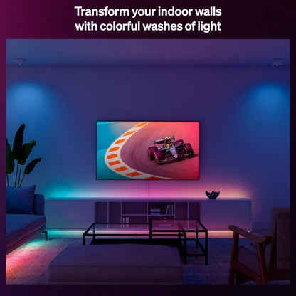 Philips Hue Essentiel LED-list 5 m med RGBIC-lys, synlig langs væg ved TV med racerbilsbillede, tekst: Forvandl dine indendørs vægge.