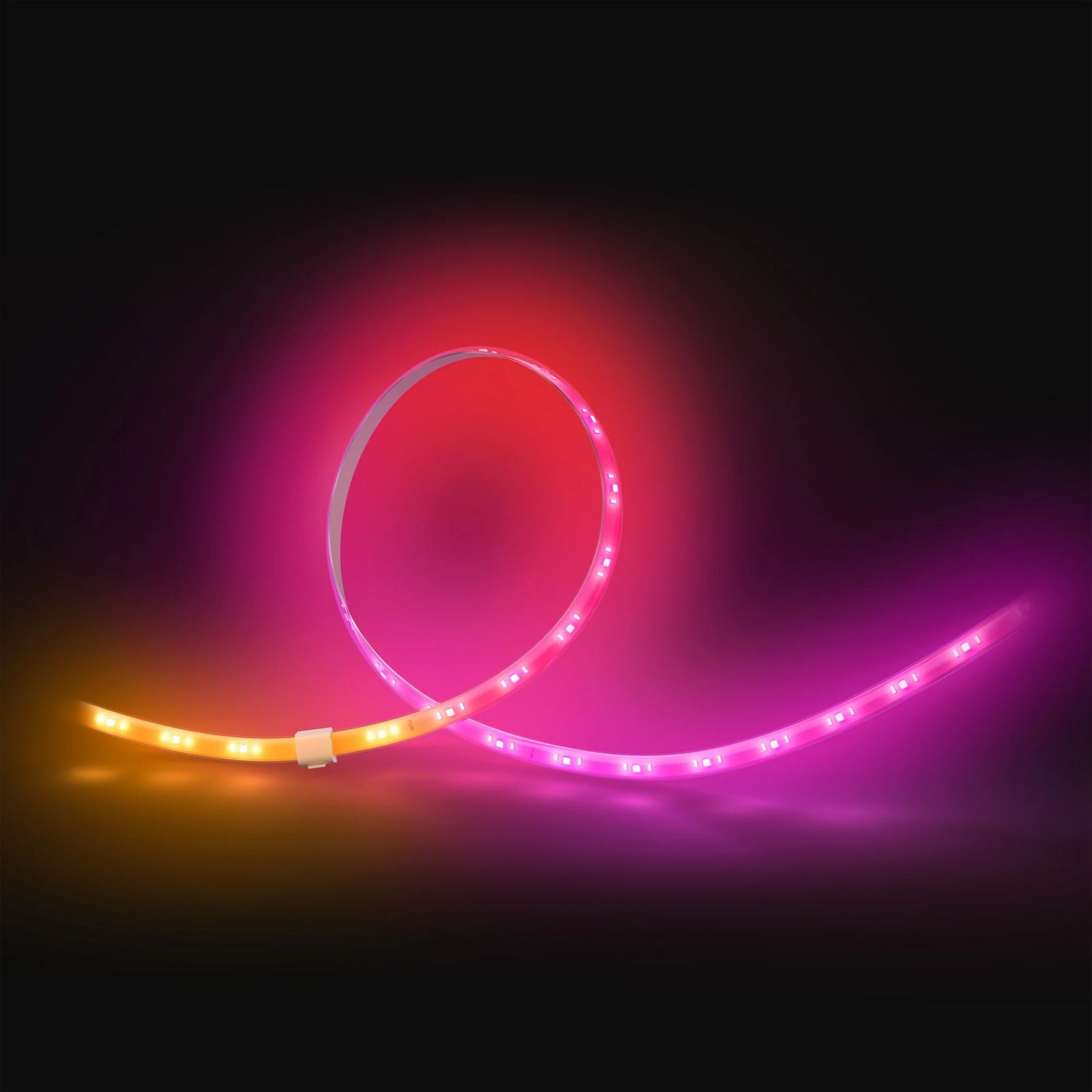 Philips Hue Flux LED-lyskæde forlængelse 5 m med pink, orange og gul Chromasync-teknologi mod mørk baggrund.
