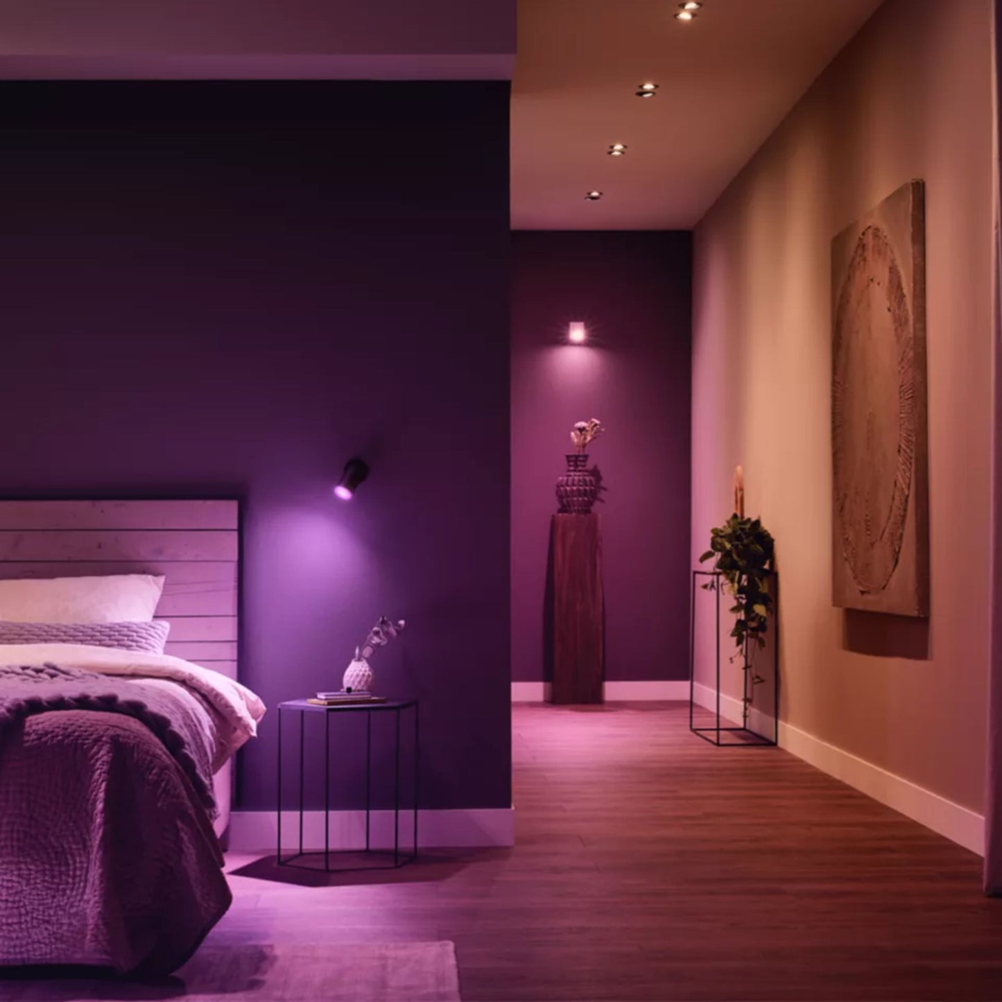 Philips Hue White  Color Ambiance GU10 Startpakke med Bridge Pro, lilla lys, trægulv, træ seng, natbord.
