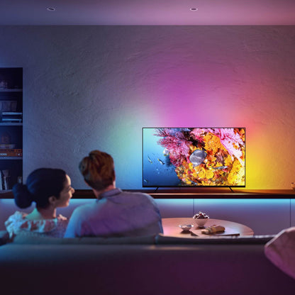Philips Hue Play Gradient Lightstrip til TV 55" monteret bag fladskærm lyser i pink, gul og blå nuance.