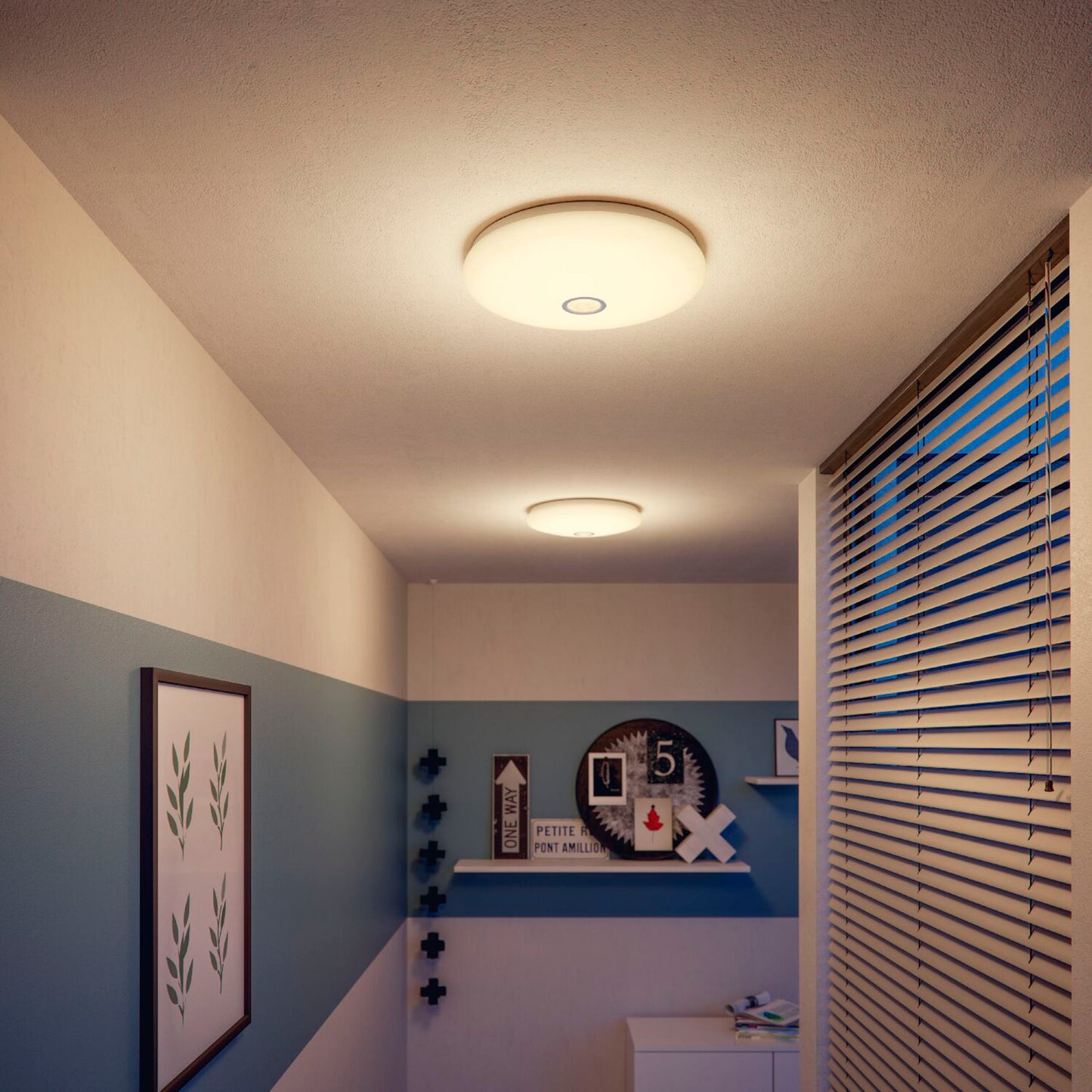 Philips Mauve LED-loftlamper med bevægelsessensor, varmt hvidt lys, indrammet grøn plakat og rundt ur i gang.