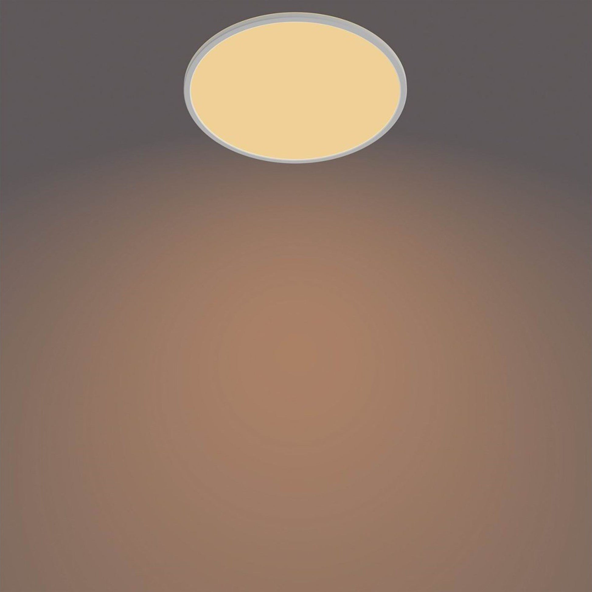 Philips Hue Loftlampe CL550 22W SceneSwitch hvid, varm gylden belysning, centreret mod mørk til taupe baggrund.