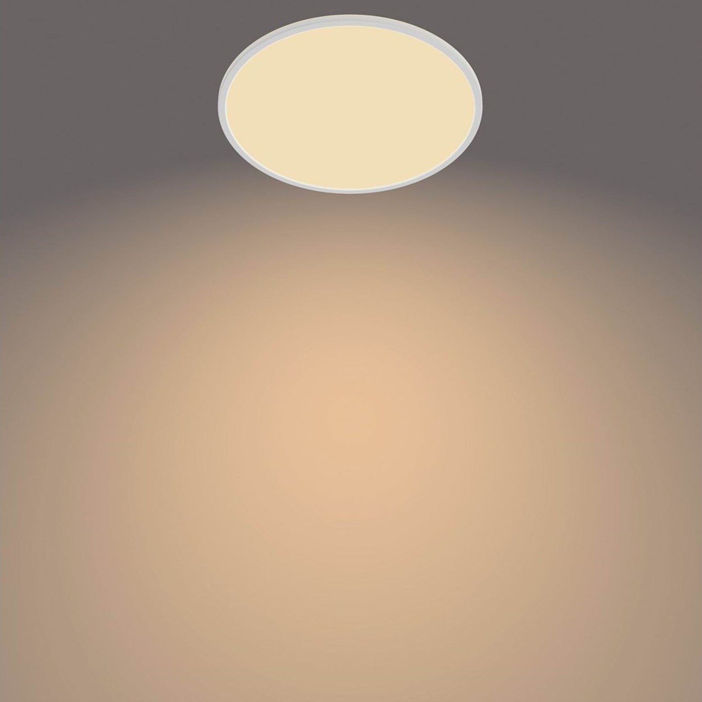 PhilipsHue Loftlampe CL550 22W SceneSwitch hvid, varmt hvidt lys, ses på grå loft med cirkulær lyseffekt.
