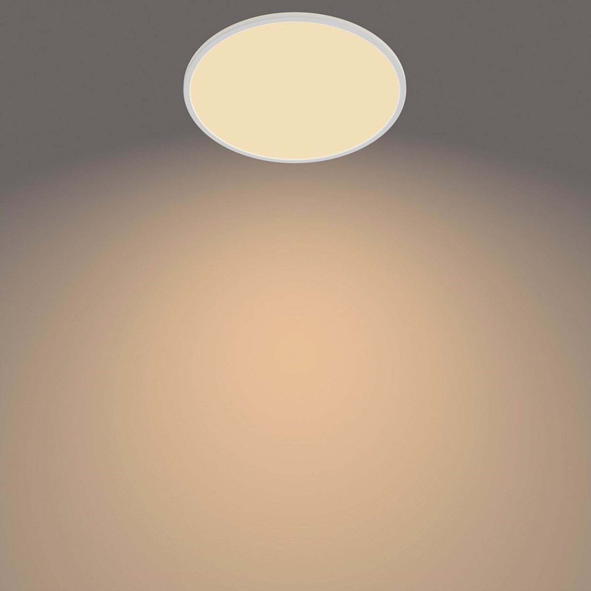 PhilipsHue Loftlampe CL550 22W SceneSwitch hvid, varmt hvidt lys, ses på grå loft med cirkulær lyseffekt.