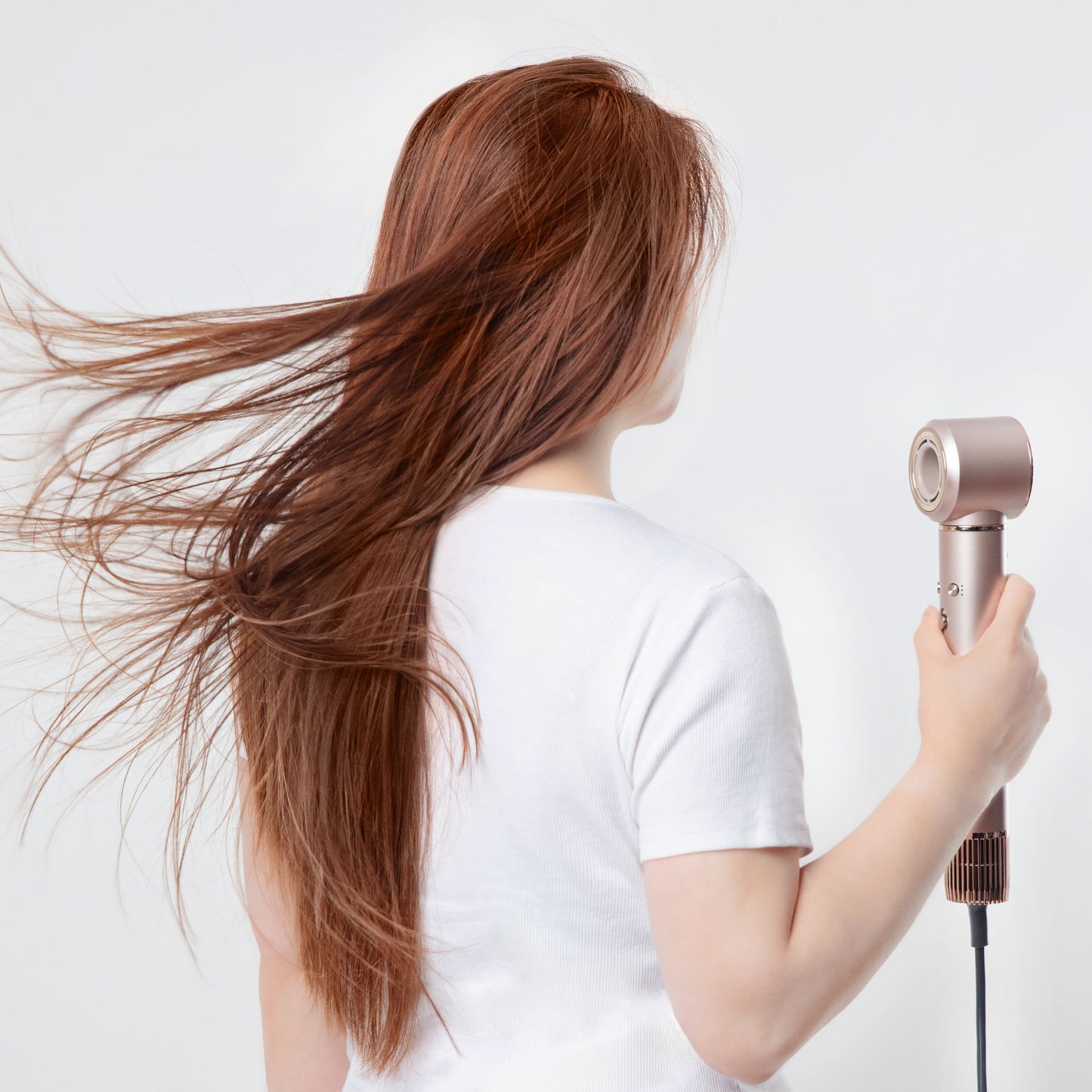 Person med langt, rødt hår holder High-speed Multistyler 7-i-1 hårtørrer med BLDC-motor.