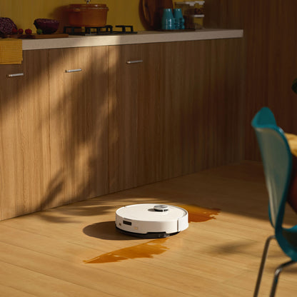 Roborock Q10 VF+ robotstøvsuger hvid med automatisk tømning og ladestation rengør spildt væske på trægulv i køkken.
