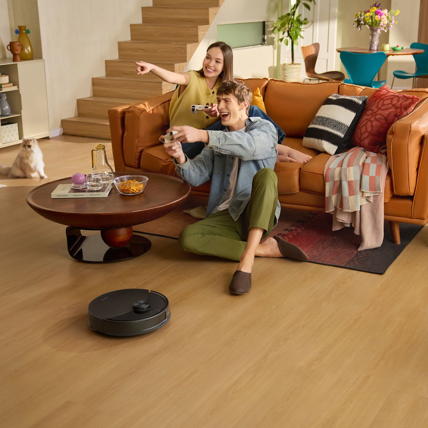 Roborock Q10 VF+ robotstøvsuger med ladestation sort, ses rengøre gulvet automatisk ved sofa og personer.