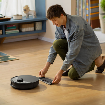 Roborock Q10 VF+ robotstøvsuger med ladestation sort, rengøres på trægulv i moderne stue.