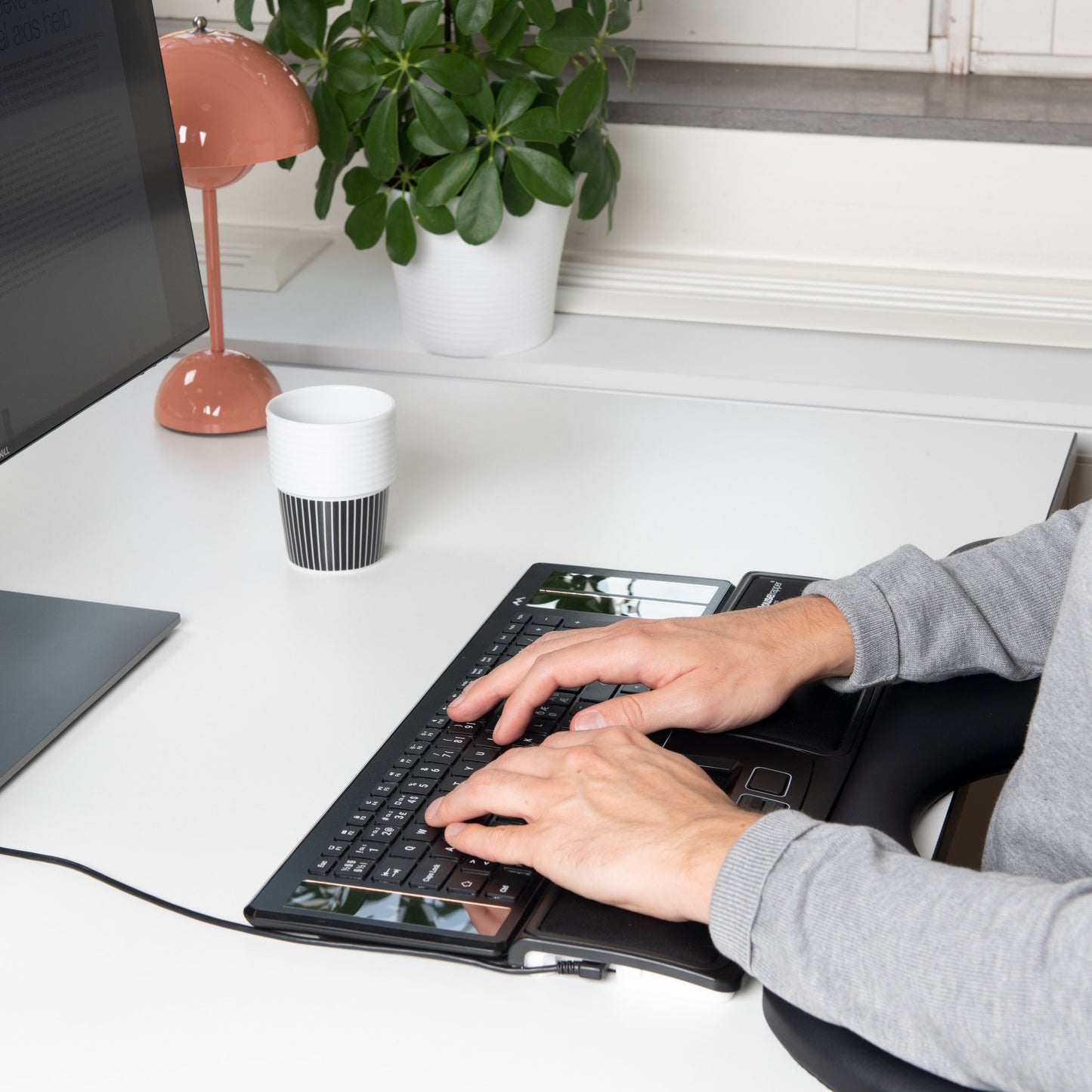 Mousetrapper Advance 2.0 ergonomisk musehåndledsstøtte sorterer på skrivebord med tastatur, skærm og tilbehør.