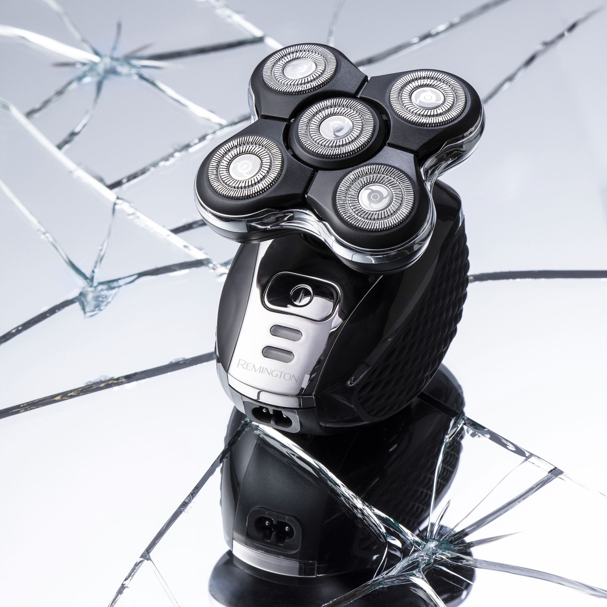 Remington Ultimate Series RX5 XR1500 barbermaskine, fem cirkulære blade, stående på sprækket reflekterende overflade.