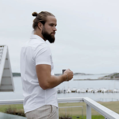 Mand med fuldskæg i hvid kortærmet skjorte holder kop, overvejer Odenson Flad børste til skæg 35 W.