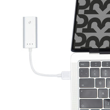 Plexgear Gigabit-netværkskort USB-A 1 Gb/s tilsluttet sølvfarvet laptop med hvidt kabel, sort/gråt mønster på skærm.