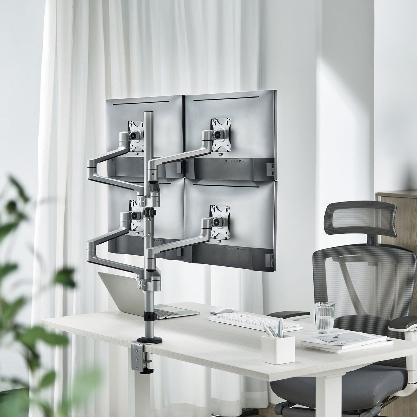Quad monitorbeslag til 4 skærme (17-32"), skrivebord med tastatur, mus, notesblok, pen og ergonomisk kontorstol.