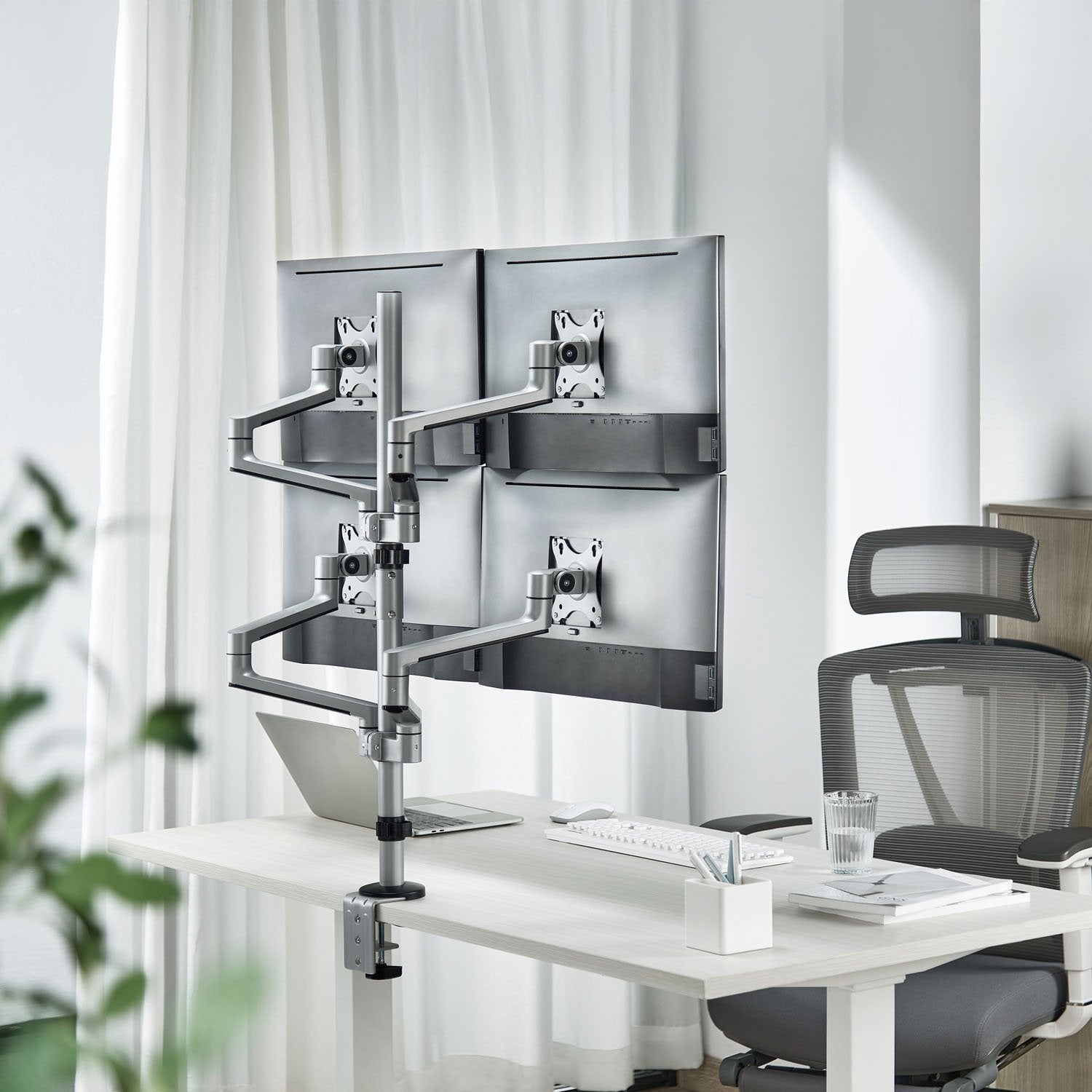 Quad monitorbeslag til 4 skærme (17-32"), skrivebord med tastatur, mus, notesblok, pen og ergonomisk kontorstol.