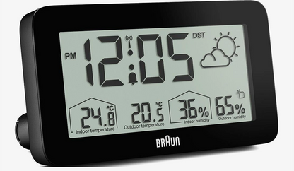 BRAUN digital vejrstation med baggrundsbelysning, LCD-display viser kl. 12:05, temperatur og luftfugtighed inde/ude, ikon for delvist overskyet.