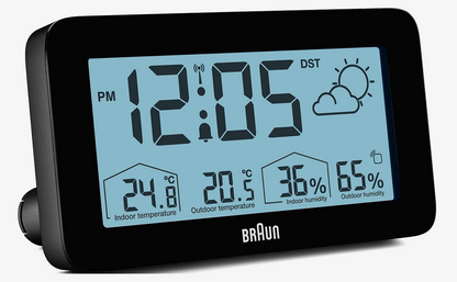 BRAUNs digitale vejrstation med baggrundsbelysning viser kl. 12:05, solrigt vejr, temperatur og luftfugtighed inde og ude.