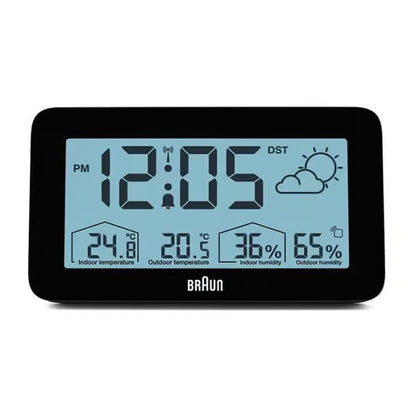 BRAUN digital vejrstation, sort, rektangulært LCD-display med blå baggrund, viser klokkeslæt, vejr, temperatur 24,8 °C/20,5 °C og luftfugtighed 36 /65 .