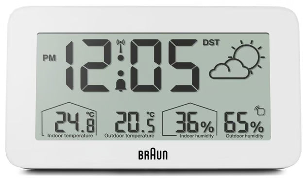 Digitalt radiostyret vækkeur i hvid, viser kl. 12:05, 24,8 °C/20,5 °C, 36 /65  luftfugtighed, ikon for delvist overskyet.