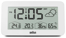 Digitalt radiostyret vækkeur i hvid, viser kl. 12:05, 24,8 °C/20,5 °C, 36 /65  luftfugtighed, ikon for delvist overskyet.