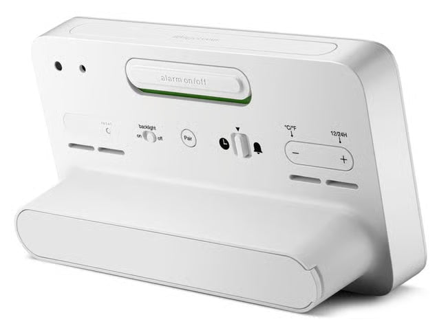 Radiostyret digitalt vækkeur i hvidt, set bagfra med knapper til temperatur, tidsformat, alarm og indstillinger.
