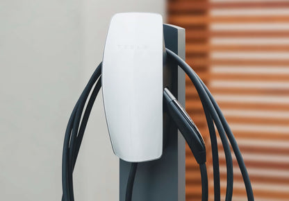 Tesla Wall Connector 22 kW hvid elbil-oplader med sorte kabler og opladerstik, monteret på mørkegråt stativ.