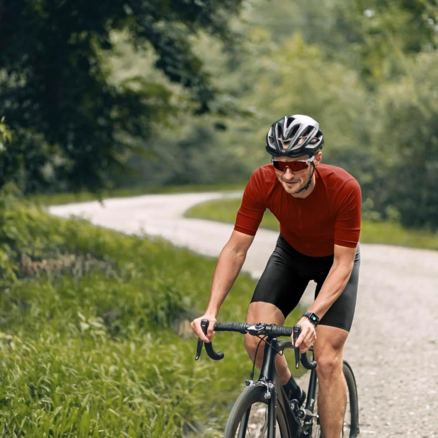 Hama 6010 Smart Watch med GPS på mandlig cyklist i rød trøje og sorte shorts, ses tydeligt på armen outdoor.