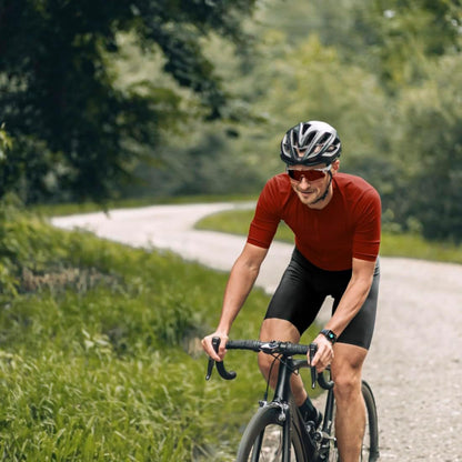 Hama 6010 Smart Watch med GPS på mandlig cyklist i rød trøje og sorte shorts, ses tydeligt på armen outdoor.