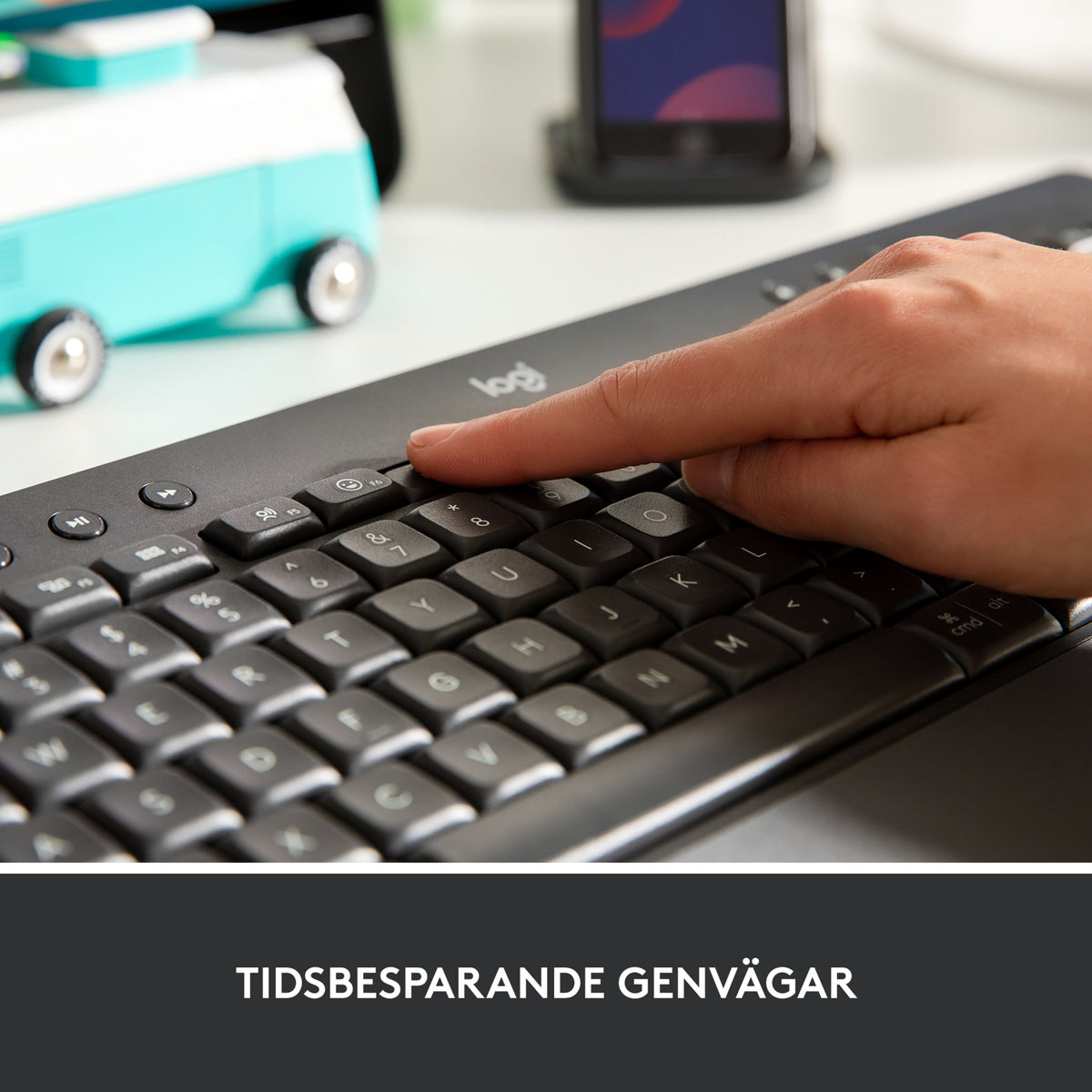 Hånden trykker på en tast på det trådløse Graphite Logitech Signature K650-tastatur med integreret håndledsstøtte.