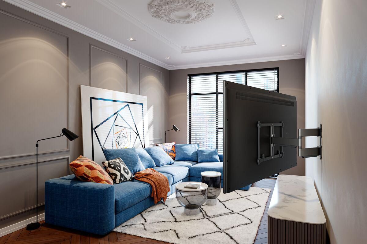 Vogels Elite TVM 5845 vægbeslag til 55-100" TV vist monteret på væg ved sofa og sofabord, sort finish.