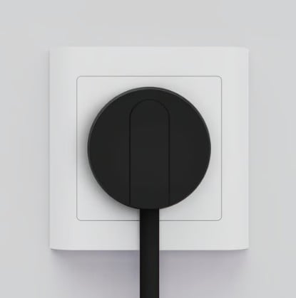 NORM K stikprop sort med jord til elektriske apparater, sat i hvid stikkontakt, sort ledning peger nedad.