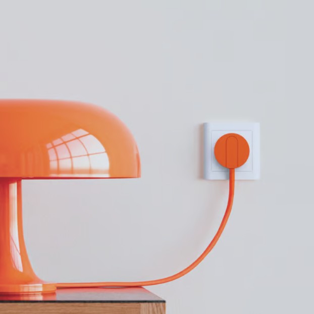 NORM K stikprop orange med jordsæt tilsluttet hvid stikkontakt, tydelig vinkel, enkel baggrund.