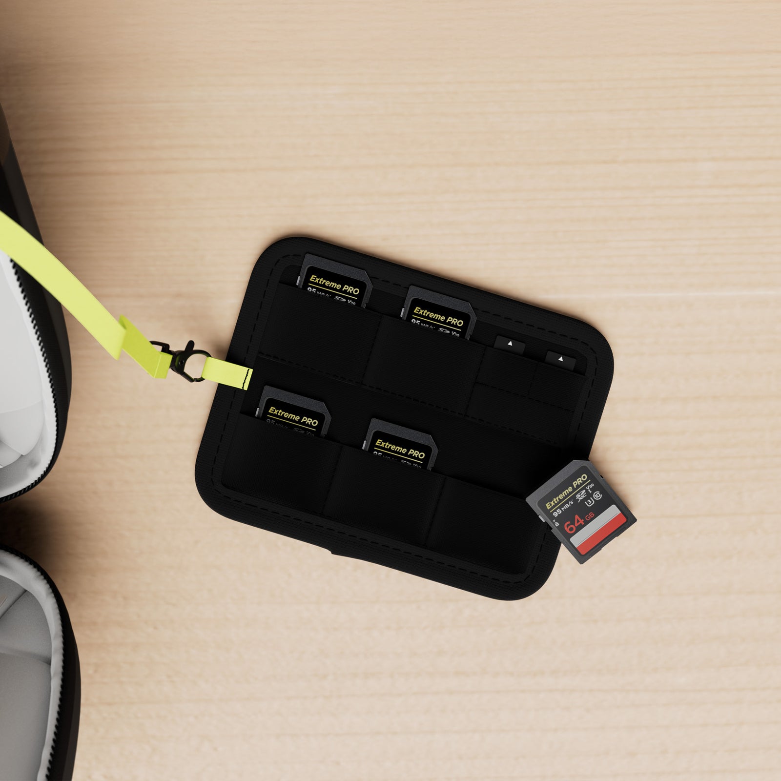Allity sort Universal Tilbehørsorganisator med flere SanDisk Extreme PRO 64GB SD-kort, ét kort delvist ude, gul rem.