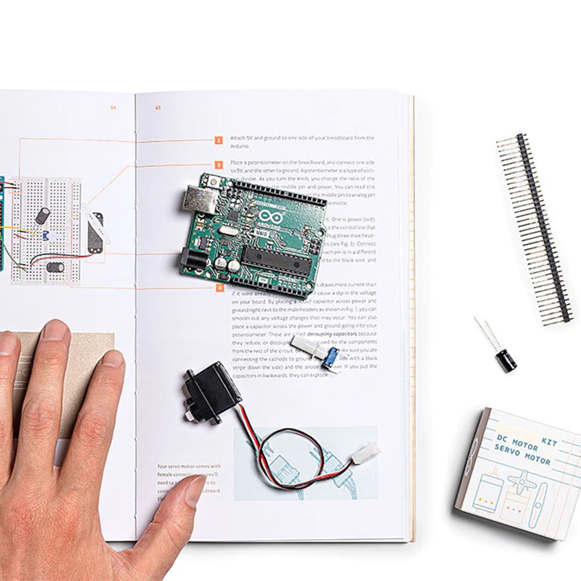 Arduino Starterpakke med Arduino board, servomotor og komponenter på åben projektbog, ekstra dele synlige.