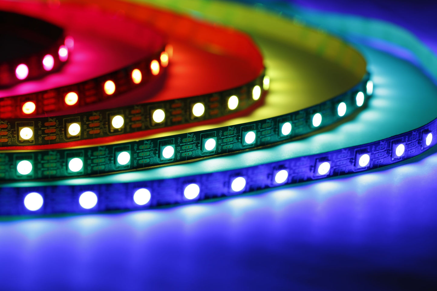 Luxorparts RGB LED-strip 1 m, flere farver lyser rødt, gult, grønt, turkis og blåt på reflekterende overflade.