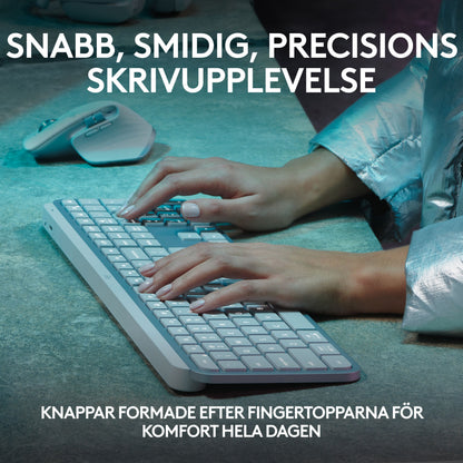 Hænderne skriver på et lysegråt, trådløst Logitech MX Keys S-tastatur med lavprofiltaster ved siden af en trådløs mus.