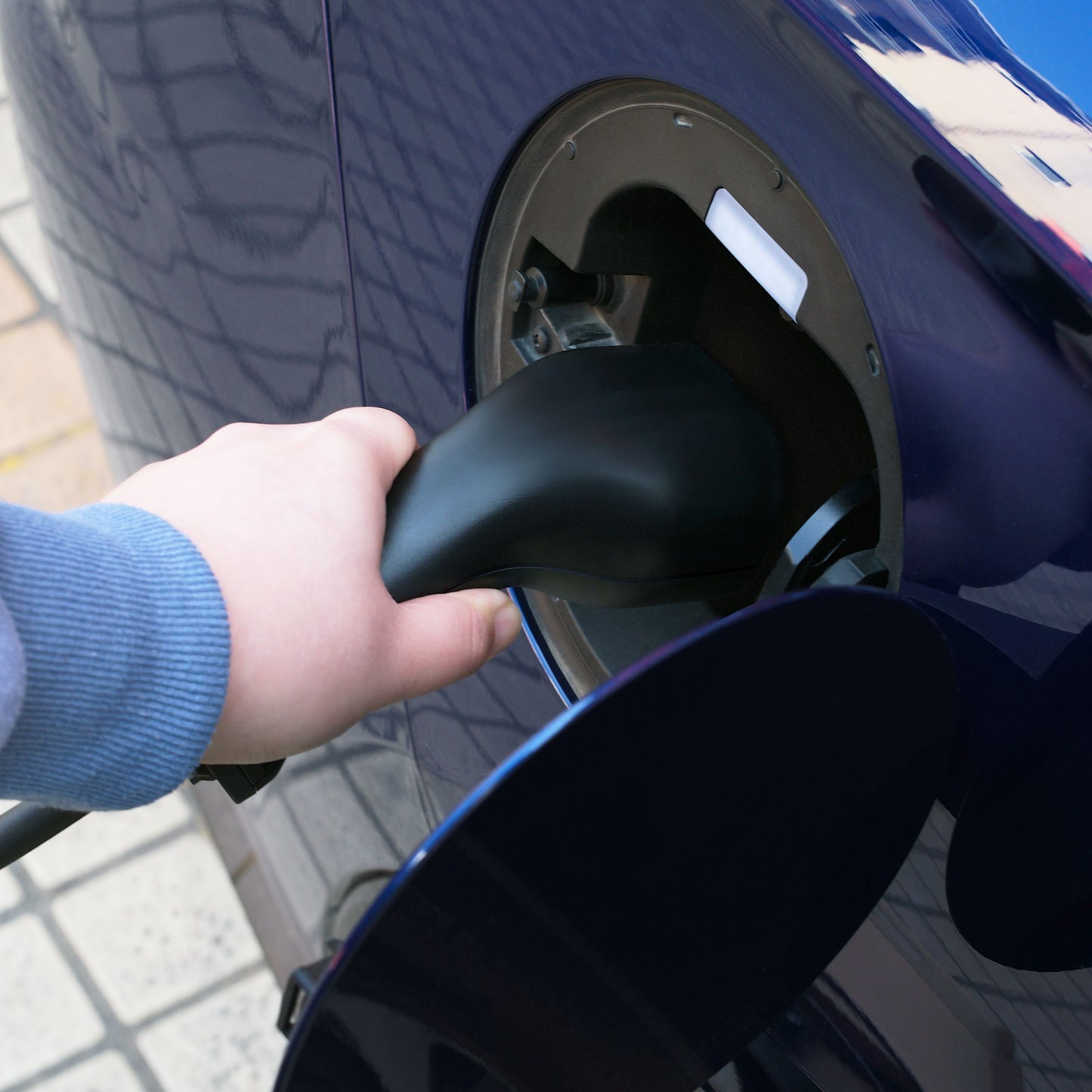 Luxorparts e-Charge Schuko til Type 2 ladekabel 5 m tilsluttes mørkeblå elbils ladeport, klinkegulv synligt.