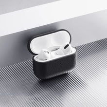 Apple AirPods Pro 3 etui i hvid i sort WOOLNUT læderetui på riflet metaloverflade ved hvidgrå kant.