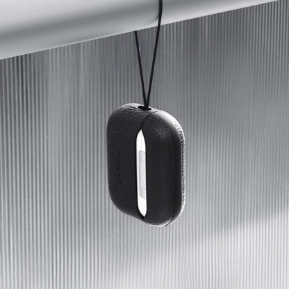 AirPods Pro 3 oplader i sort WOOLNUT læderetui hænger fra sort snor på metallisk stang, lodret rillet baggrund.