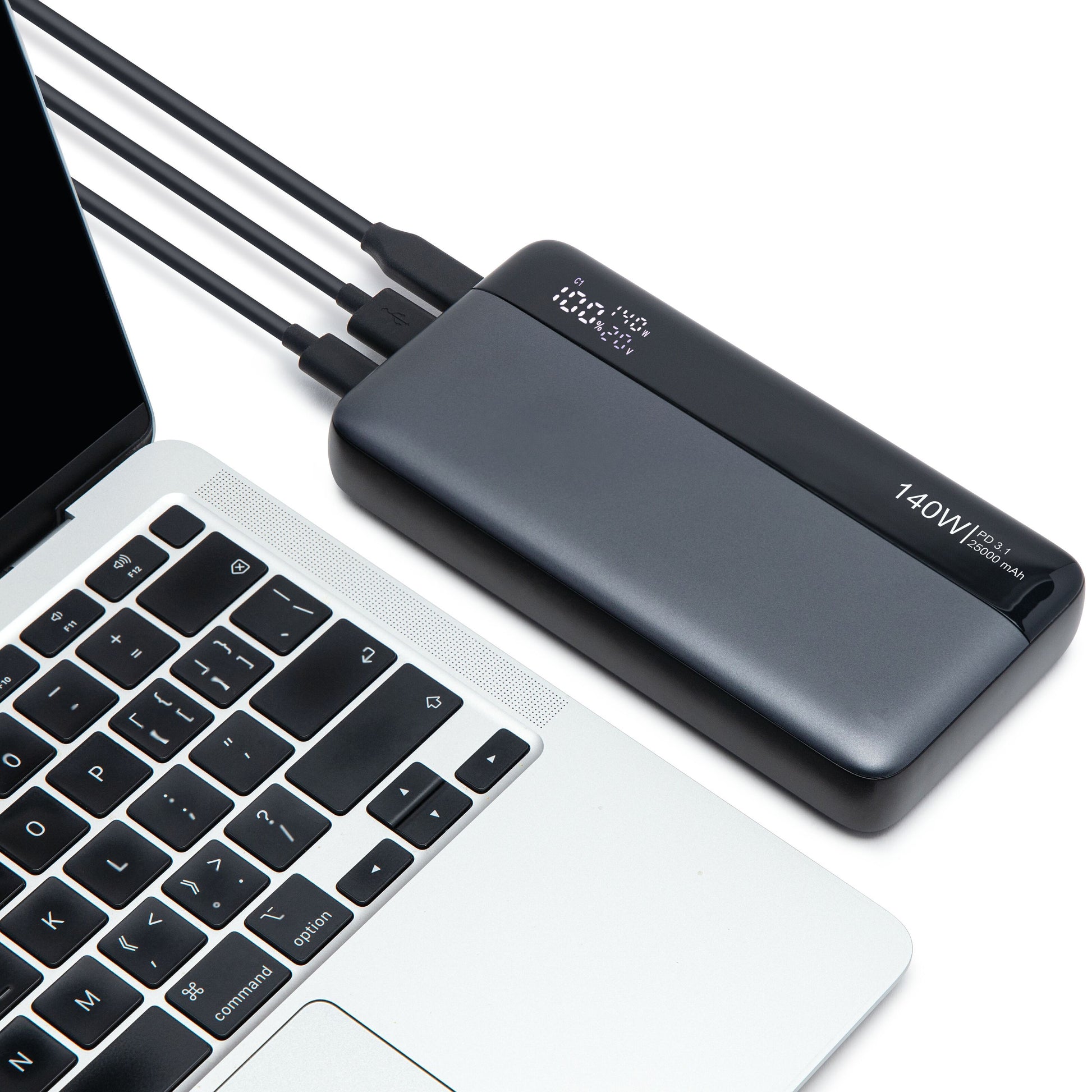 Powerbank 140W 25000mAh sort tilsluttet sølvfarvet laptop via USB-C, til ekstra kabler tilsluttet.