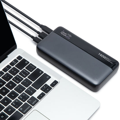 Powerbank 140W 25000mAh sort tilsluttet sølvfarvet laptop via USB-C, til ekstra kabler tilsluttet.